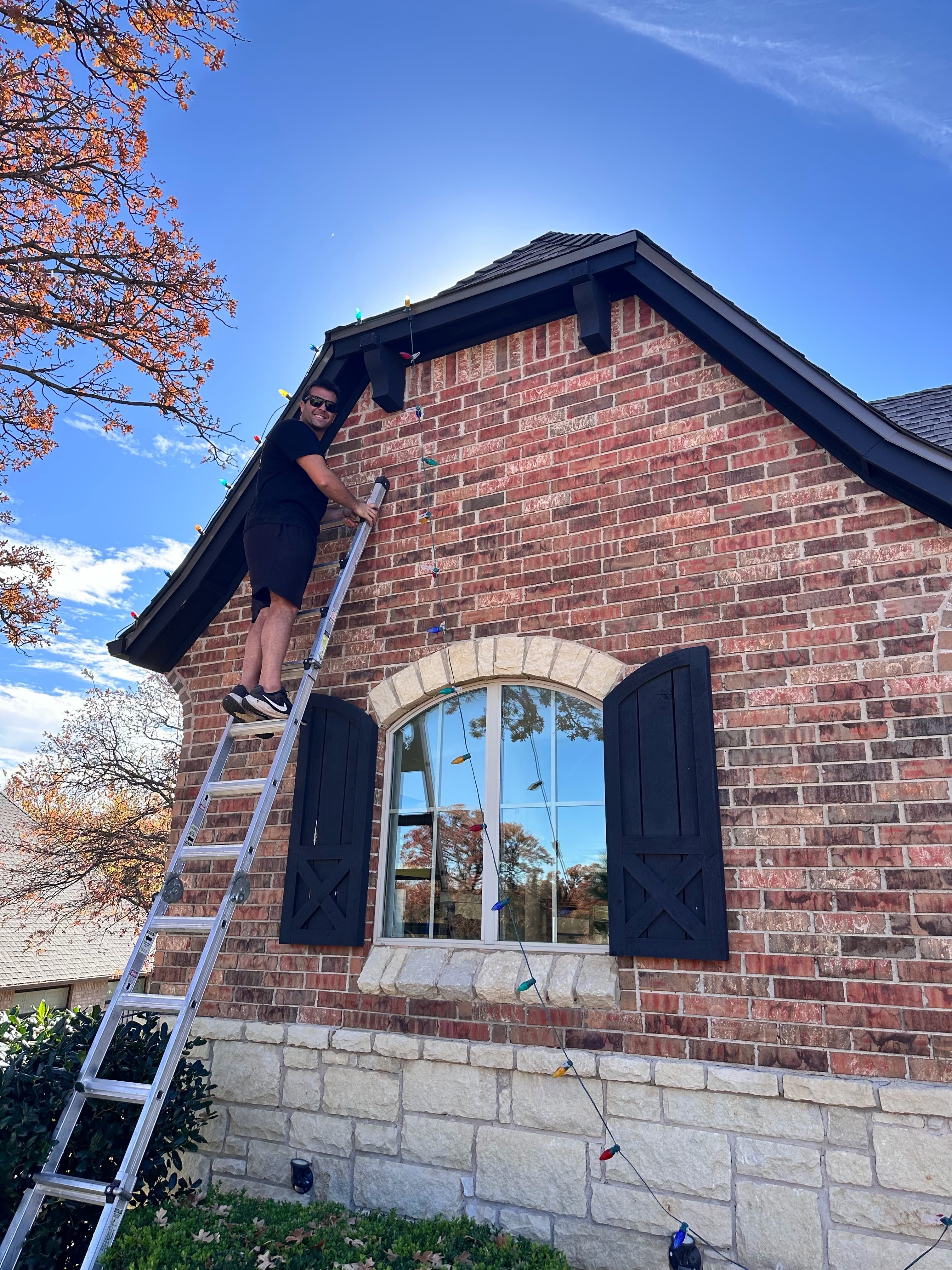 Tim Smoley of Timmy Time Anytime installing Christmas lights on a brick home in Edmond, Oklahoma